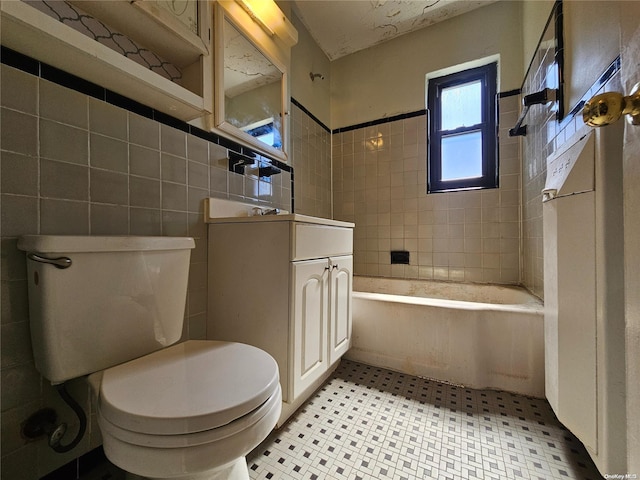 full bathroom featuring vanity, toilet, tiled shower / bath, and tile walls