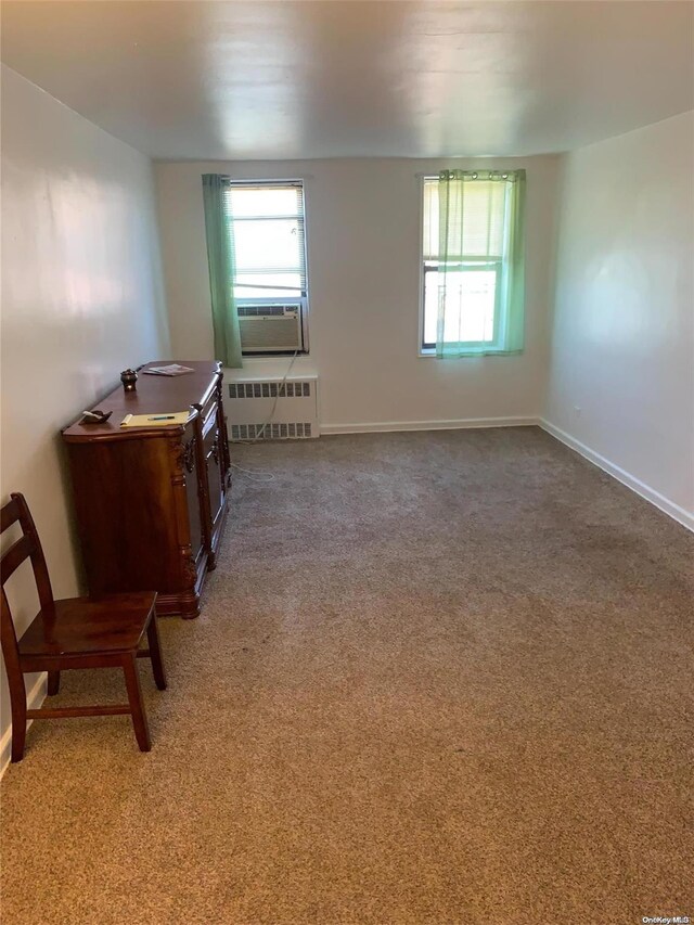 interior space with carpet floors, radiator heating unit, and cooling unit