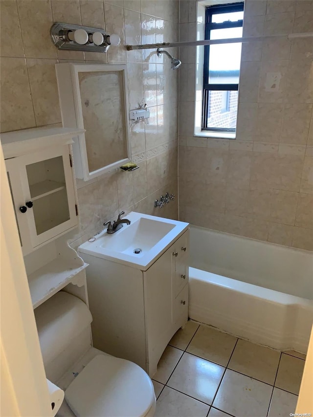 full bathroom with vanity, tile patterned floors, tiled shower / bath, toilet, and tile walls