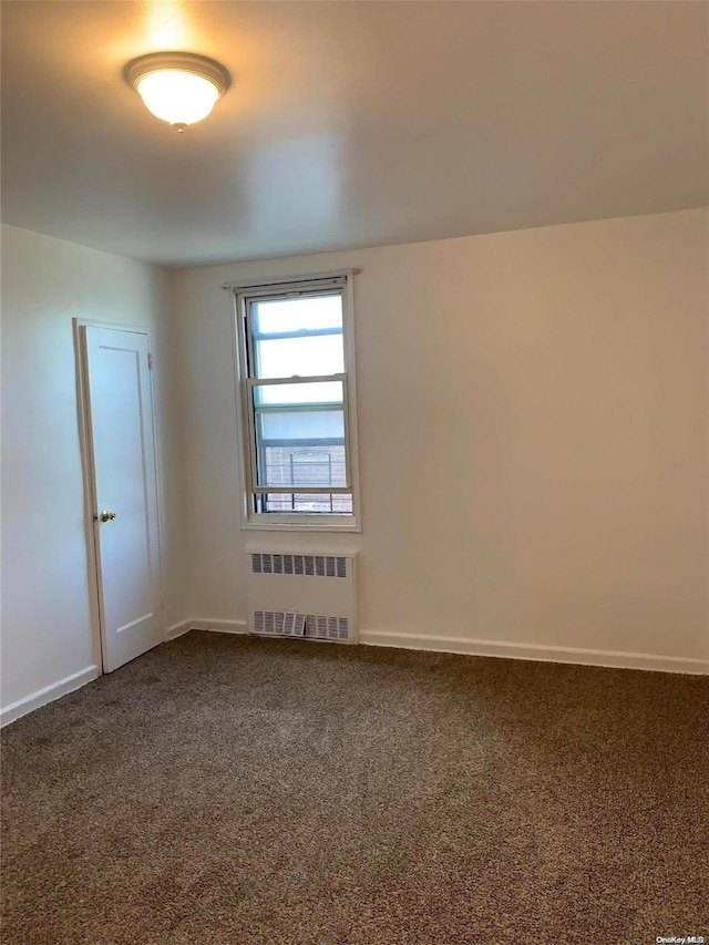 carpeted spare room featuring radiator