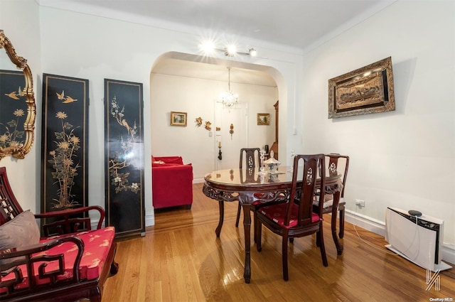 dining space with hardwood / wood-style flooring and a notable chandelier