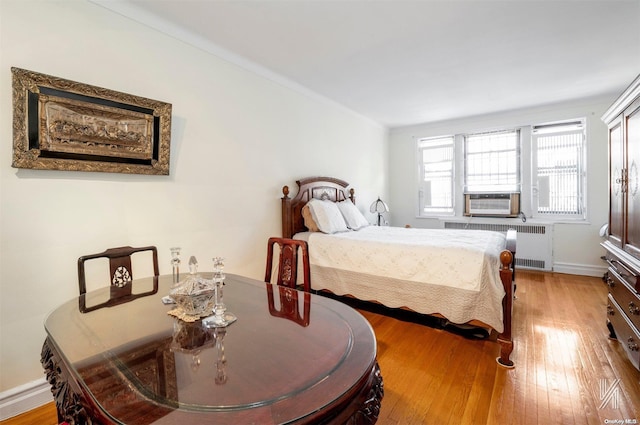 bedroom with radiator, cooling unit, and wood-type flooring