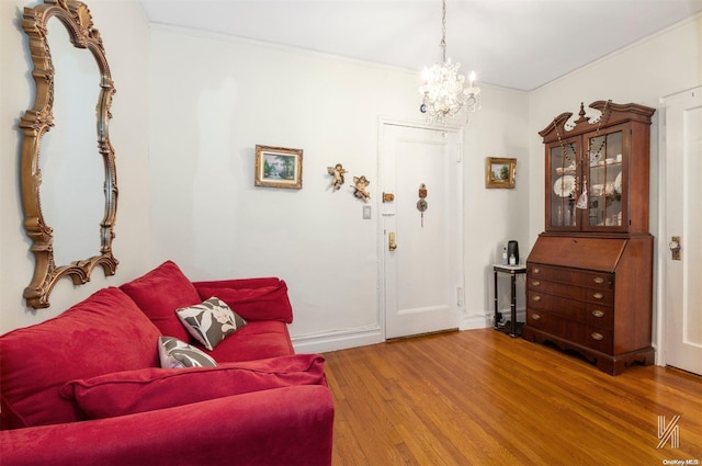 living room with wood-type flooring, ornamental molding, and a notable chandelier