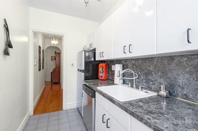 kitchen featuring tasteful backsplash, white cabinetry, sink, and stainless steel dishwasher