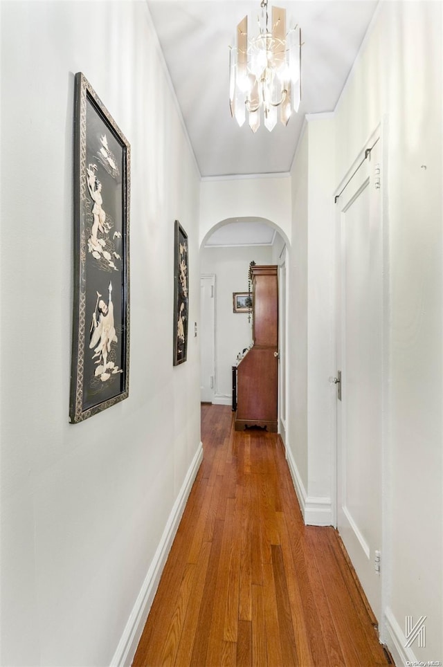 hallway with wood-type flooring and a chandelier