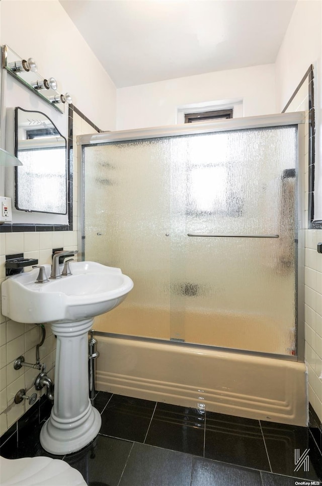 bathroom featuring backsplash, tile patterned flooring, tile walls, and combined bath / shower with glass door