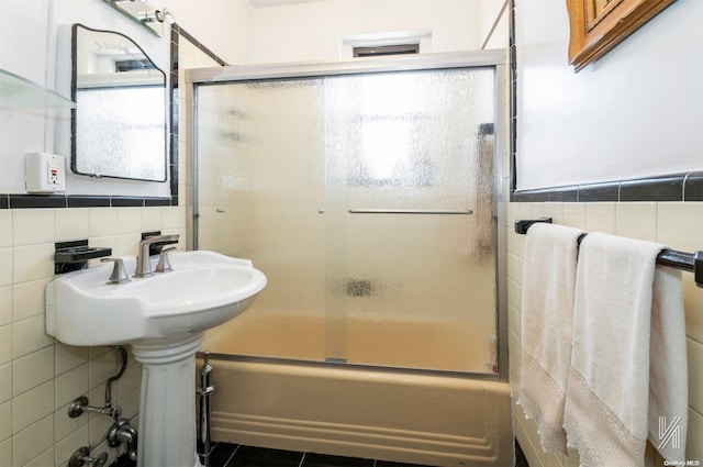 bathroom with shower / bath combination with glass door, plenty of natural light, and tile walls