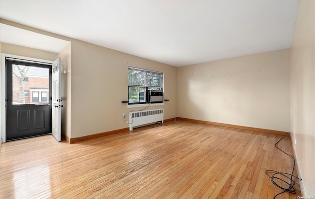 unfurnished living room featuring a healthy amount of sunlight, radiator heating unit, and light hardwood / wood-style flooring