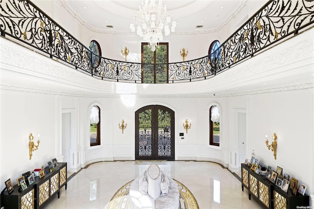 entrance foyer with french doors, a towering ceiling, and ornamental molding