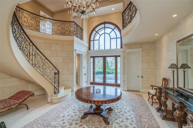 entrance foyer featuring a chandelier, french doors, a towering ceiling, and tile walls