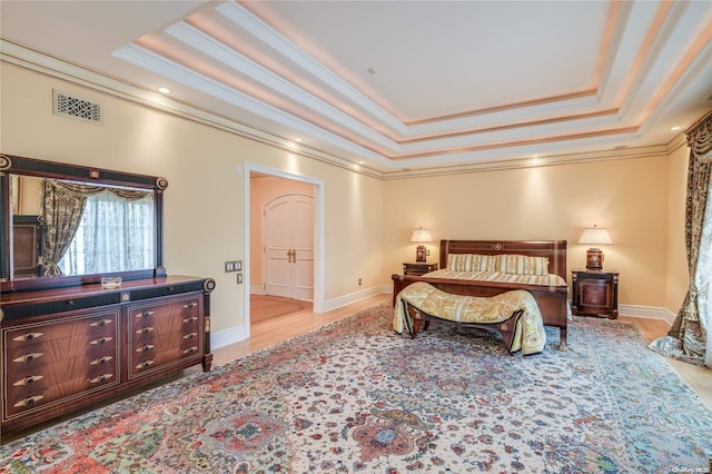 bedroom with light hardwood / wood-style floors, a raised ceiling, and ornamental molding