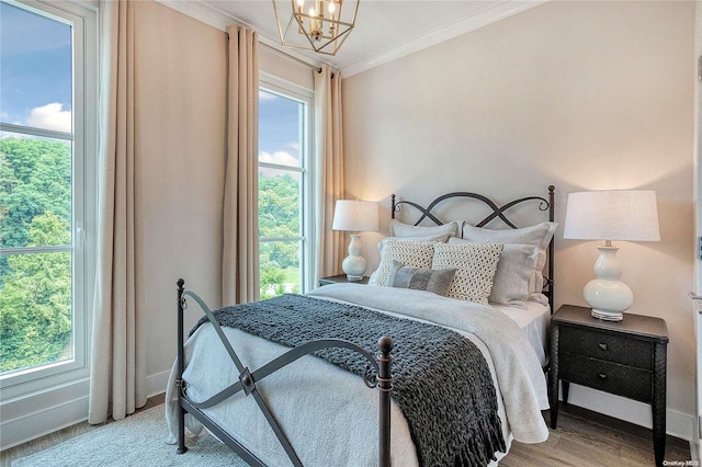 bedroom with light wood-type flooring, an inviting chandelier, and ornamental molding