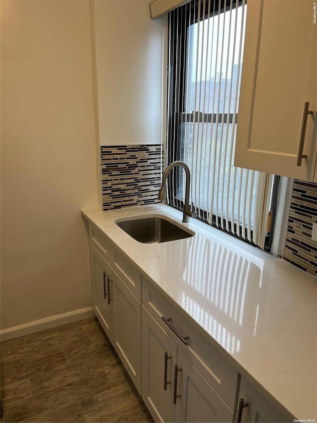 kitchen featuring light stone countertops, sink, dark wood-type flooring, and tasteful backsplash