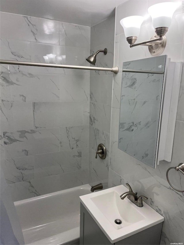 bathroom featuring vanity, an inviting chandelier, tiled shower / bath, tile walls, and tasteful backsplash