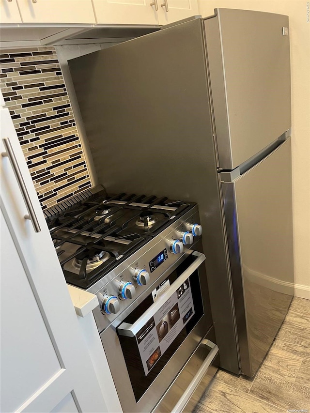 kitchen featuring tasteful backsplash, light hardwood / wood-style flooring, and white cabinets