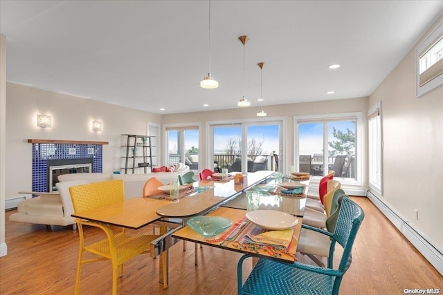 dining area featuring baseboard heating, a fireplace, and light hardwood / wood-style flooring