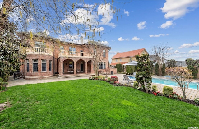 rear view of property featuring a lawn, a patio area, and a balcony