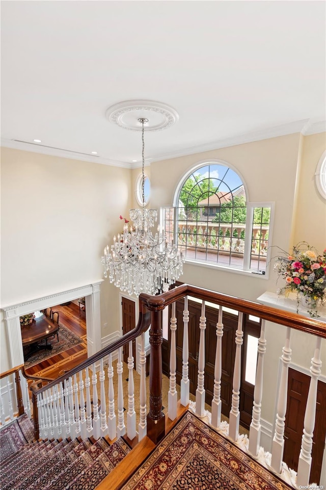 stairs featuring hardwood / wood-style flooring, a notable chandelier, and crown molding