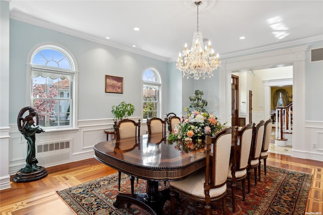 dining space with a healthy amount of sunlight, light hardwood / wood-style floors, crown molding, and a chandelier