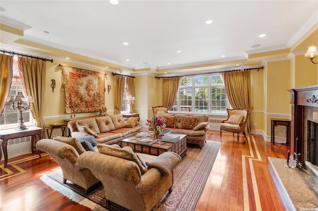 living room featuring a high end fireplace, light wood-type flooring, and ornamental molding