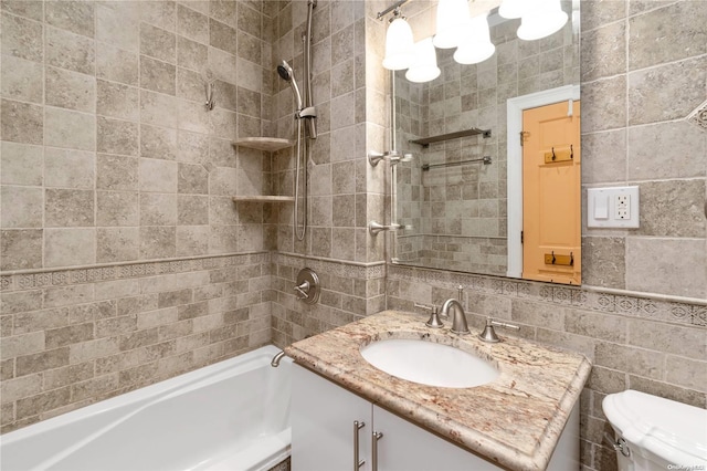 full bathroom with tiled shower / bath, vanity, toilet, and tile walls