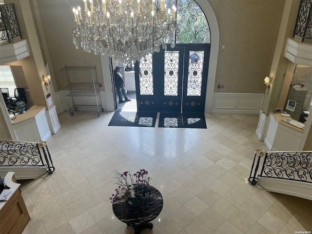 tiled entryway featuring french doors and an inviting chandelier