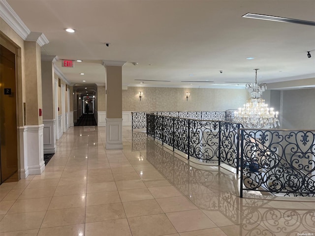 hallway with light tile patterned floors, an inviting chandelier, ornate columns, and ornamental molding