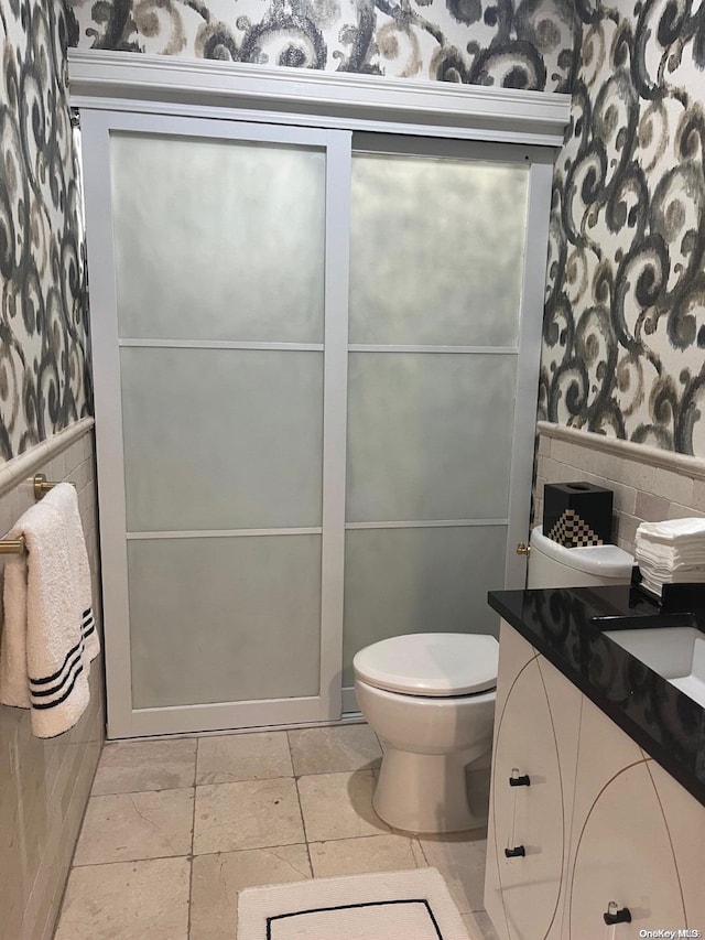 bathroom featuring vanity, toilet, and tile walls