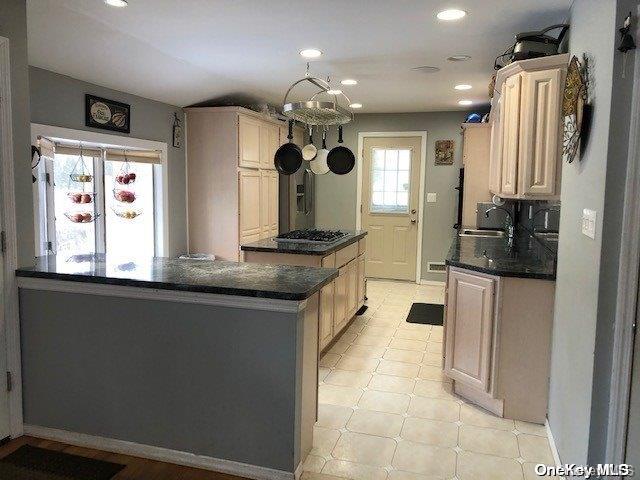 kitchen featuring a sink, a center island, recessed lighting, stainless steel gas stovetop, and baseboards