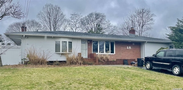 view of front of house featuring a front lawn, fence, brick siding, and a chimney