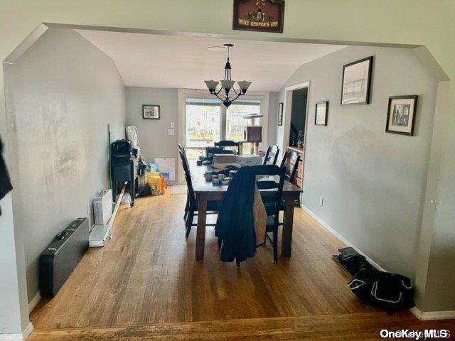 dining room featuring baseboards, a notable chandelier, wood finished floors, and vaulted ceiling