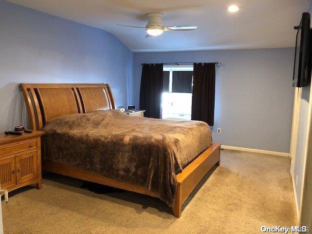 bedroom featuring baseboards, lofted ceiling, light colored carpet, and a ceiling fan