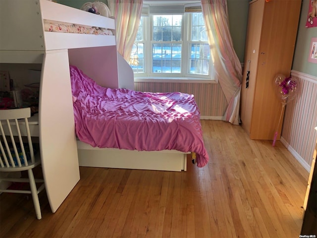 bedroom with wainscoting and hardwood / wood-style floors