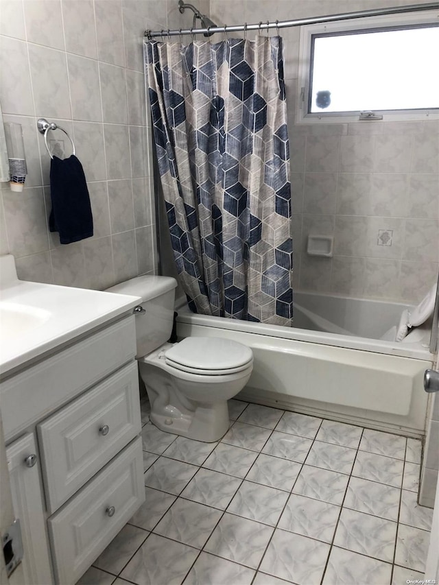 bathroom featuring tile patterned flooring, toilet, vanity, shower / bath combination with curtain, and tile walls