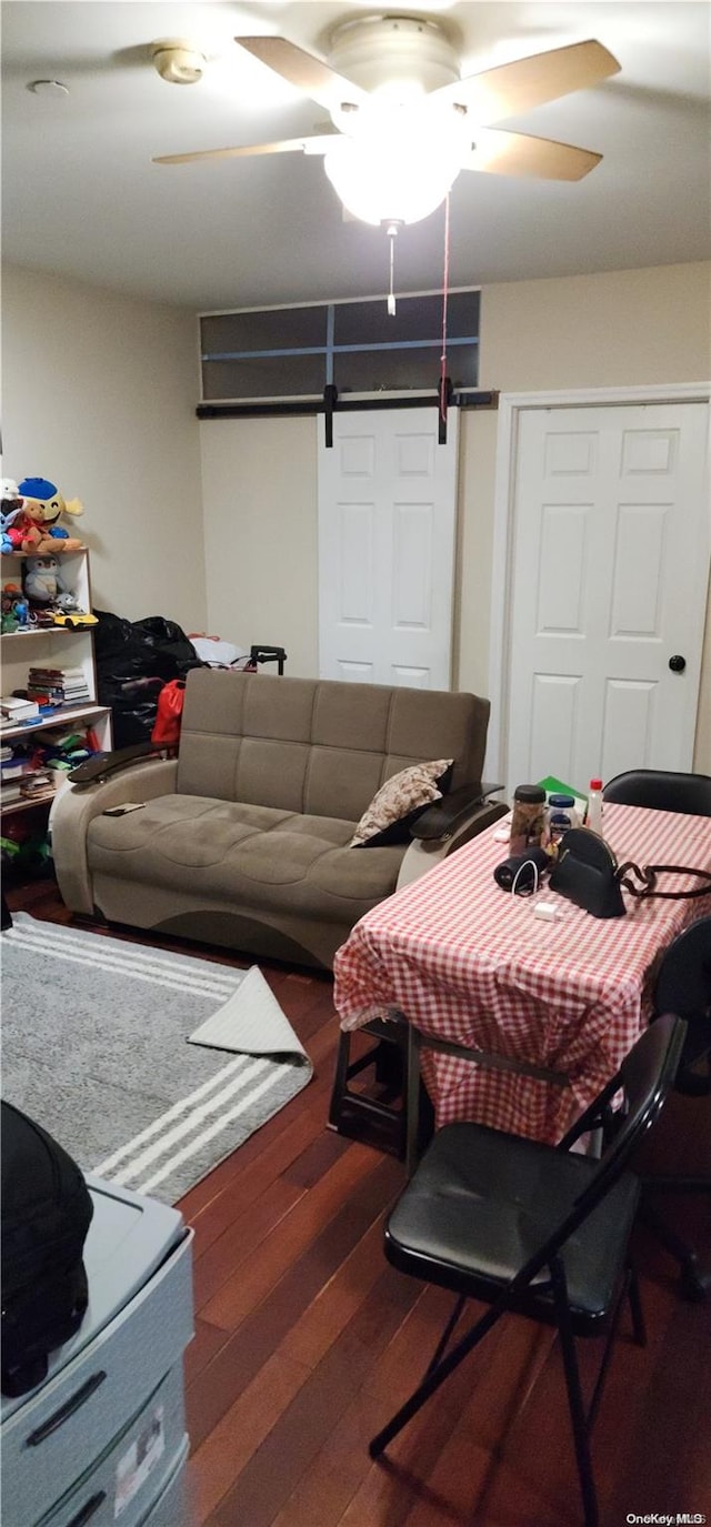 living room with hardwood / wood-style flooring, ceiling fan, and a barn door