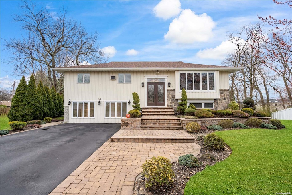 raised ranch featuring french doors, a front lawn, fence, and aphalt driveway