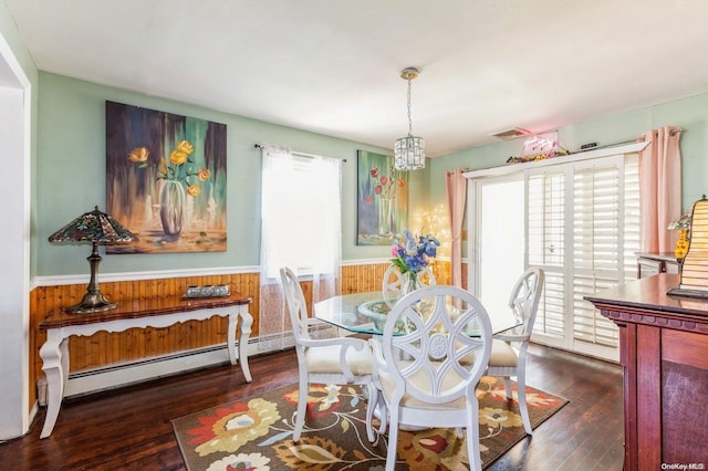 dining area with a notable chandelier, dark hardwood / wood-style floors, baseboard heating, and wooden walls