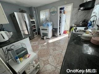 kitchen featuring tile patterned floors, stainless steel fridge, and white cabinets