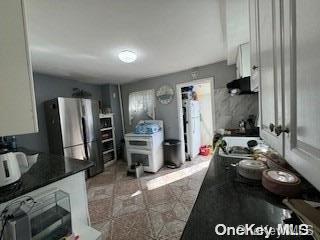 kitchen featuring white cabinetry and stainless steel refrigerator