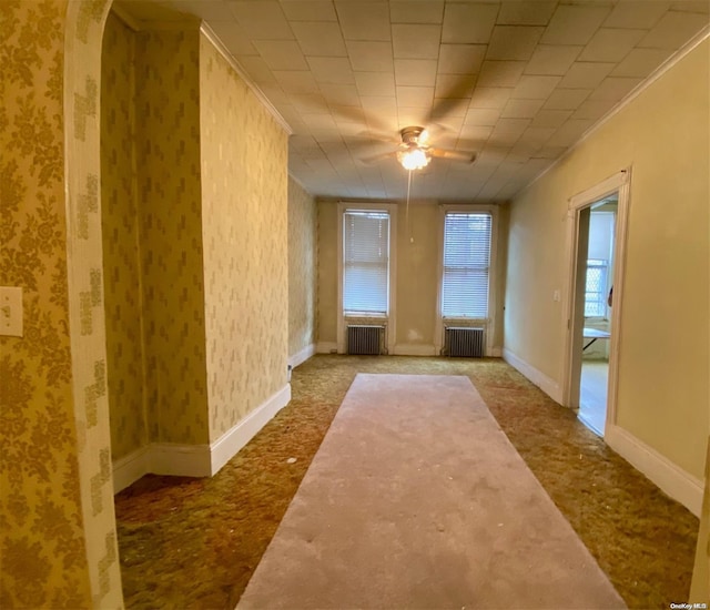 unfurnished room with carpet, ceiling fan, and radiator