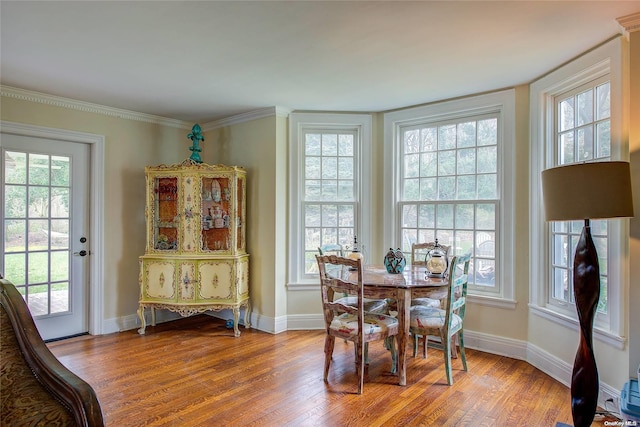 dining space with light wood-type flooring, crown molding, and a wealth of natural light