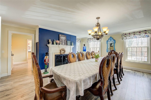 dining area with light wood-type flooring, crown molding, a wealth of natural light, and a chandelier