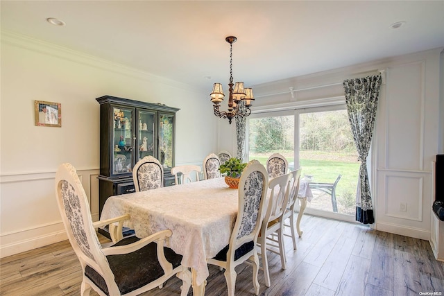 dining area featuring crown molding, light hardwood / wood-style floors, and an inviting chandelier