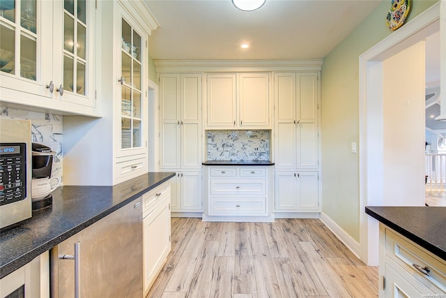 kitchen featuring backsplash, dark stone countertops, light hardwood / wood-style flooring, and white cabinets