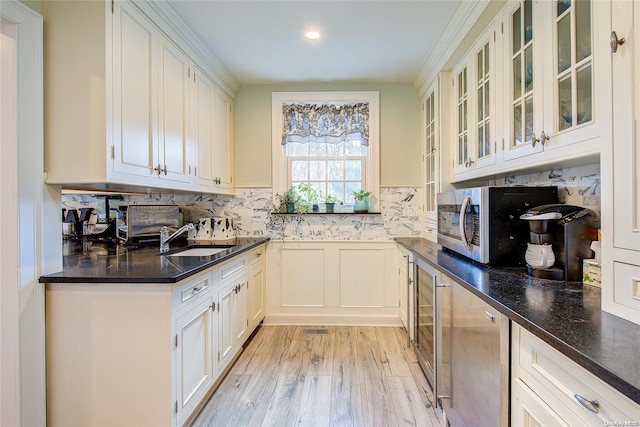 kitchen featuring white cabinets, light wood-type flooring, sink, and tasteful backsplash