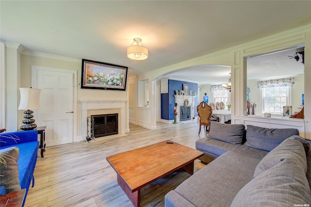 living room featuring light hardwood / wood-style floors, crown molding, and an inviting chandelier