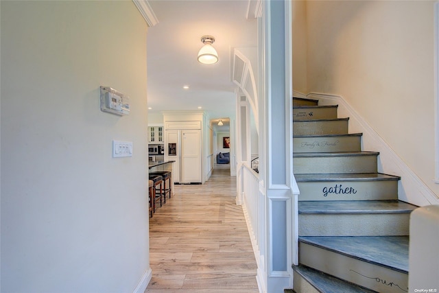 stairs with wood-type flooring and ornamental molding