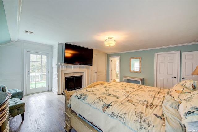 bedroom with hardwood / wood-style floors, crown molding, and access to outside