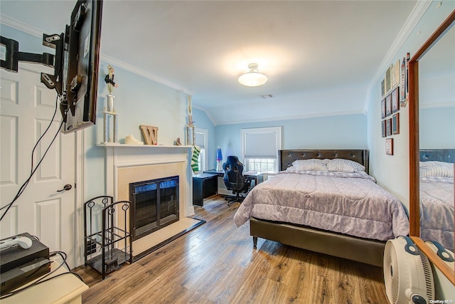 bedroom with ornamental molding, vaulted ceiling, and hardwood / wood-style flooring