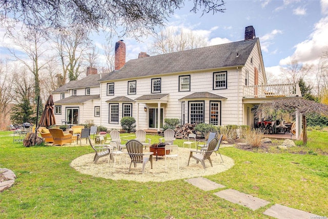 back of house featuring a yard, a balcony, and a fire pit